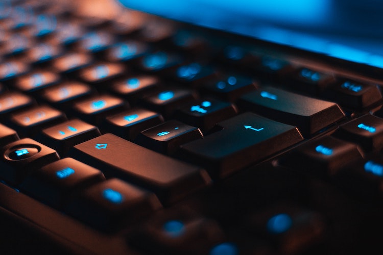close up of a black computer keyboard with blue backlit keys
